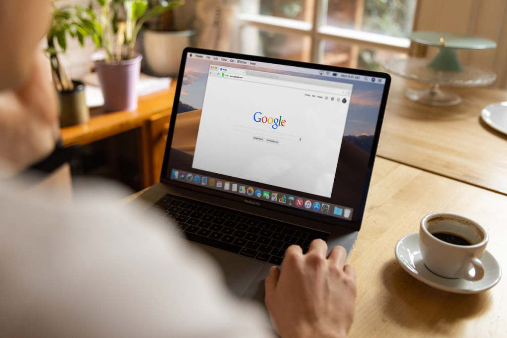 person typing on laptop with search engine results page blurred in background, no face visible