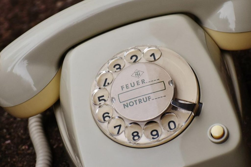 an old rotary telephone on a wooden shop counter, no people, no text