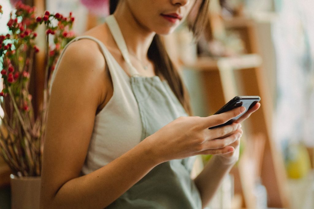 small business owner checking phone with map pin and star rating icons overlay graphic, no faces visible