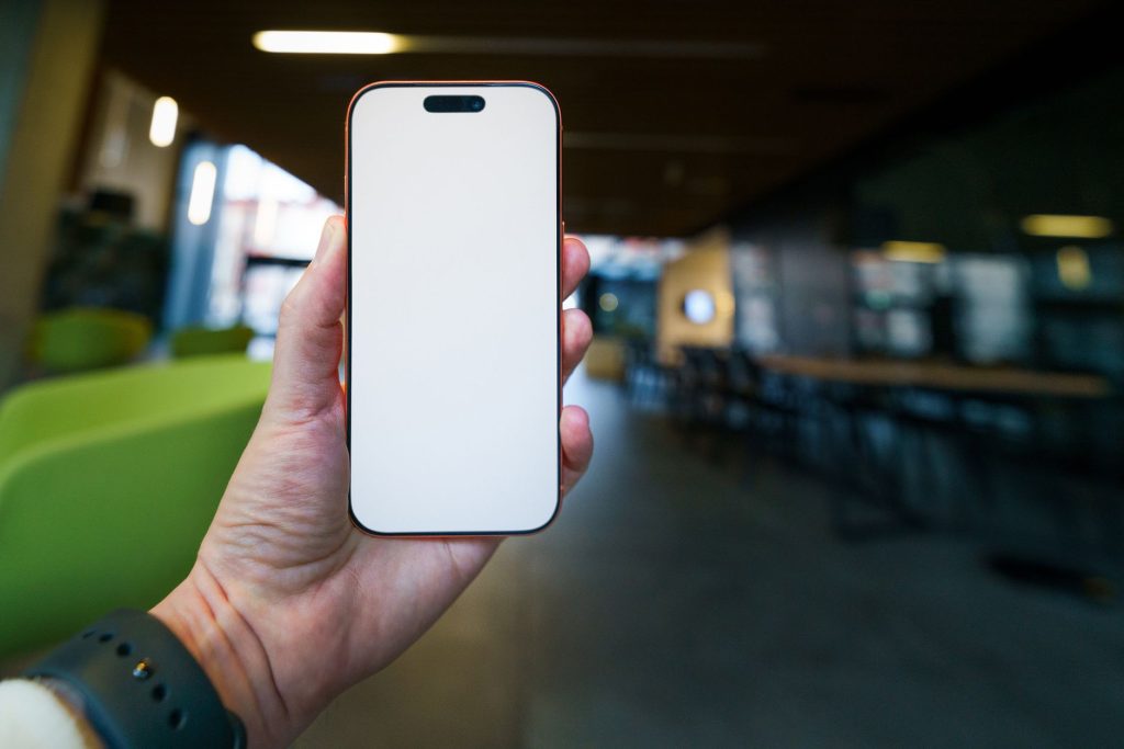 hand holding smartphone with search app open, blurred office background, no face